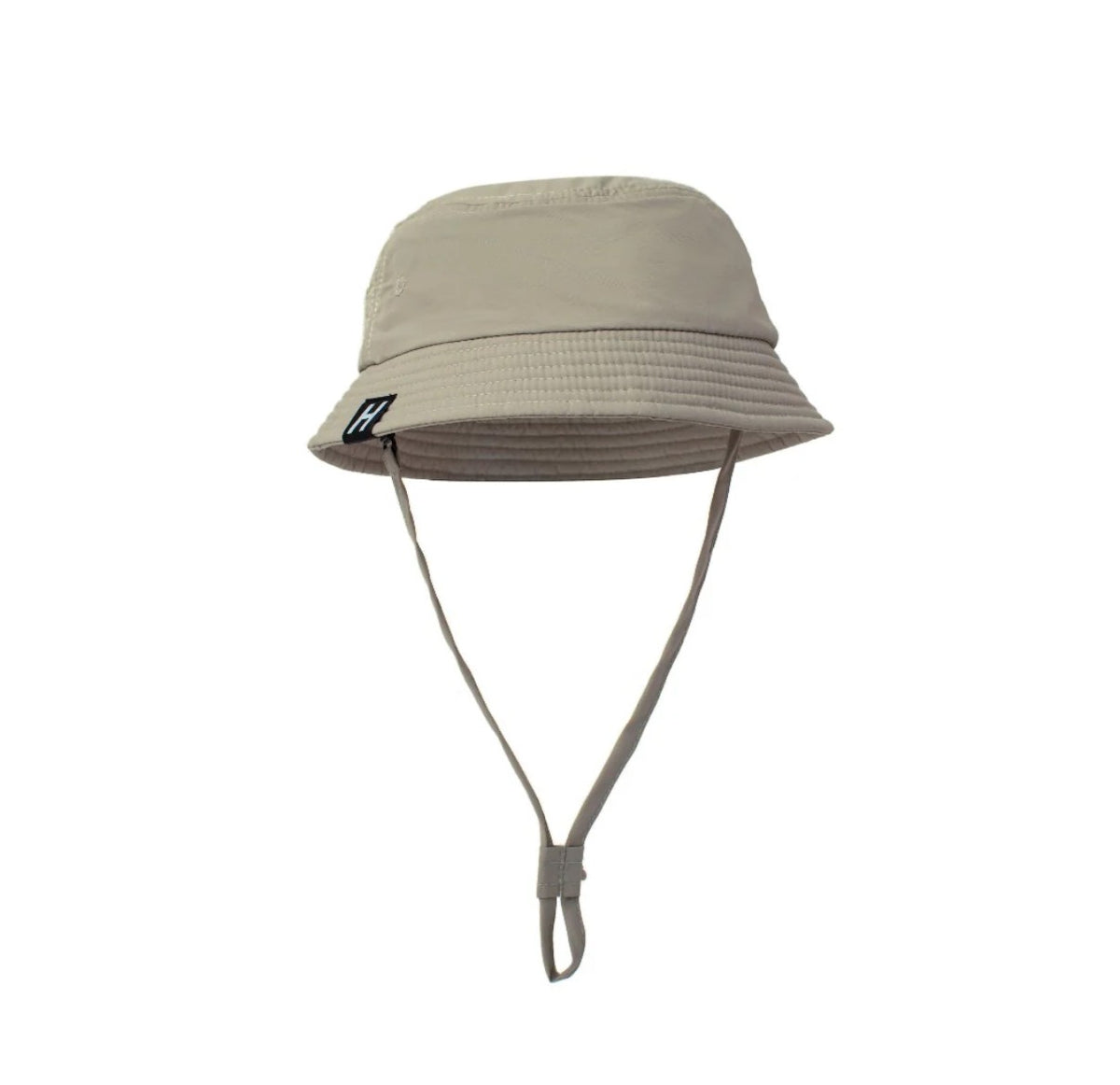 A tan bucket hat with and adjustable, removable chin strap. The logo "H" is on a small black clamp label on the brim. 